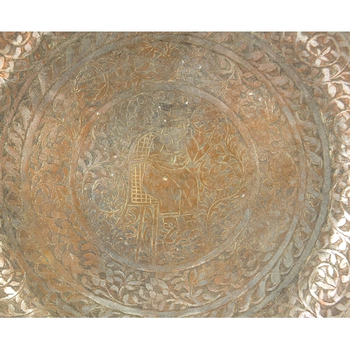 201 - Turkish silvered copper dish engraved with a figure seated in the centre surrounded by flowers and f... 