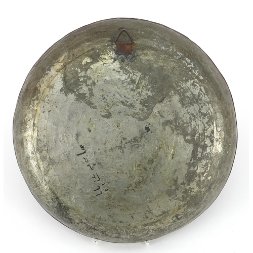 201 - Turkish silvered copper dish engraved with a figure seated in the centre surrounded by flowers and f... 