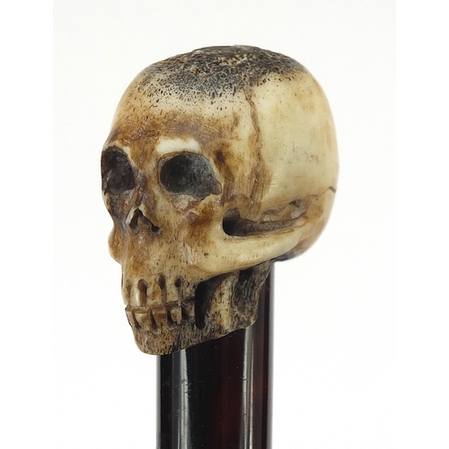 329 - Ebony walking stick with carved bone the pommel in the form of a skull, the cane 90cm in length