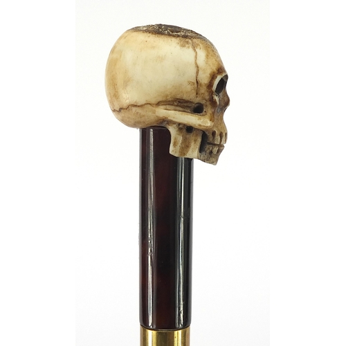 329 - Ebony walking stick with carved bone the pommel in the form of a skull, the cane 90cm in length