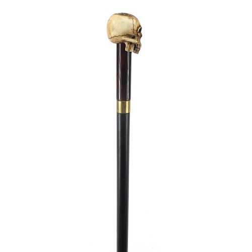 329 - Ebony walking stick with carved bone the pommel in the form of a skull, the cane 90cm in length