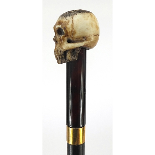 329 - Ebony walking stick with carved bone the pommel in the form of a skull, the cane 90cm in length