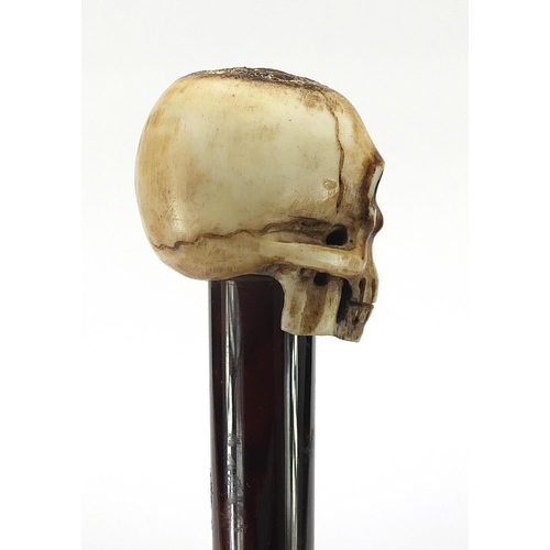 329 - Ebony walking stick with carved bone the pommel in the form of a skull, the cane 90cm in length