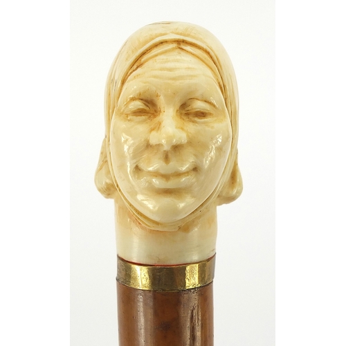 323 - Hardwood and ebony walking stick with carved ivory pommel in the form of a lady's head, 90cm in leng... 