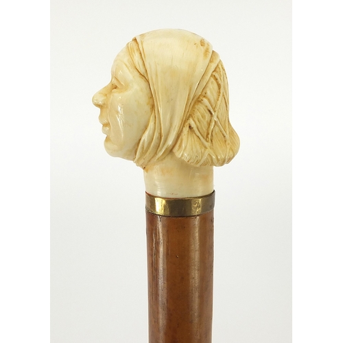 323 - Hardwood and ebony walking stick with carved ivory pommel in the form of a lady's head, 90cm in leng... 