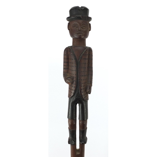 186 - Tribal interest wooden short staff carved with a gentleman wearing a bowler hat and jacket, shorts a... 