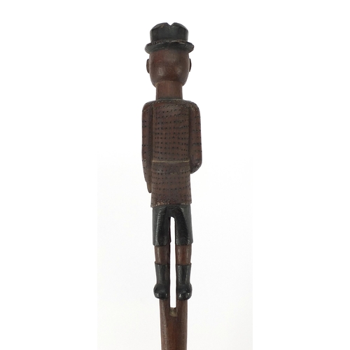 186 - Tribal interest wooden short staff carved with a gentleman wearing a bowler hat and jacket, shorts a... 