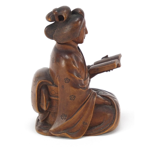 51 - Japanese erotic carved hardwood okimono of a lady kneeling down reading a book, character mark to th... 