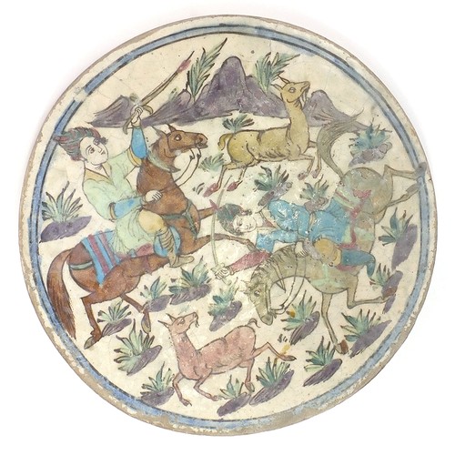 205 - Turkish Kutahya pottery tile hand painted with warriors on horseback, 39.5cm in diameter