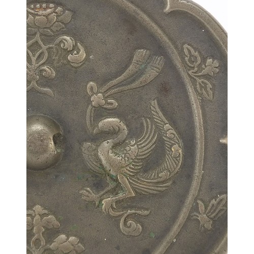 121 - Chinese patinated bronze hand mirror cast with phoenixes and flowers, 15.5cm in diameter