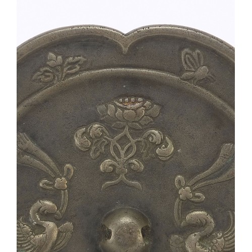 121 - Chinese patinated bronze hand mirror cast with phoenixes and flowers, 15.5cm in diameter