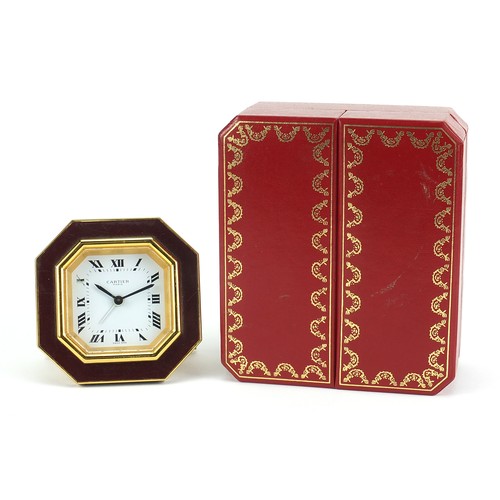 268 - Cartier red and gold coloured desk strut clock, the dial having Roman numerals, housed in a red pres... 