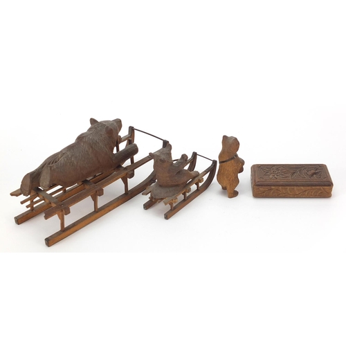 15 - Three carved Black Forest bears and a matchbox including two riding sleds, the largest 15cm in lengt... 