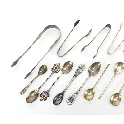 2221 - Georgian and later silver sugar tongs and spoons including enamelled souvenir teaspoons, the largest... 