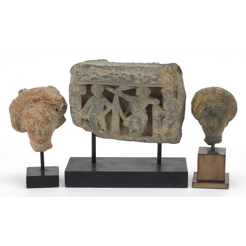 452 - Indian carved stone fragment and two terracotta heads, each raised on later stands, the largest over... 
