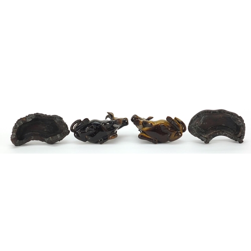 62 - Pair of Chinese carved tiger's eye water buffalos, each raised on a carved wood base, 8.5cm in lengt... 