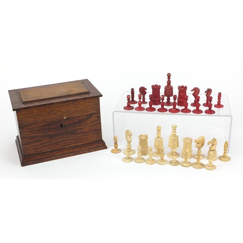 1959 - Half stained carved bone chess pieces, housed in an antique oak box, the largest piece 8.5cm high