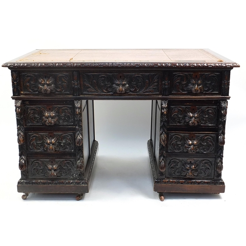 698A - Oak twin pedestal desk with tooled leather top above a series of drawers, carved with lions heads, 8... 