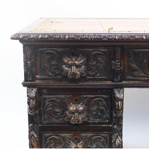 698A - Oak twin pedestal desk with tooled leather top above a series of drawers, carved with lions heads, 8... 