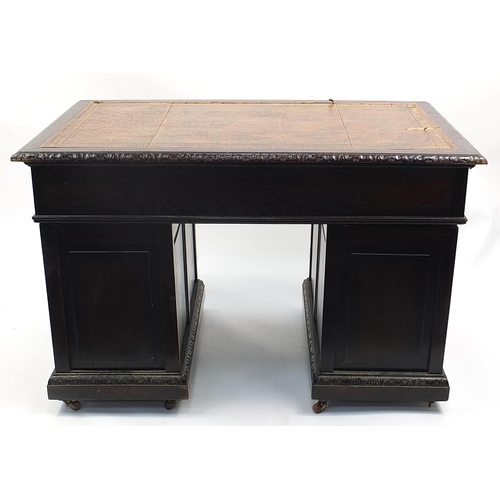 698A - Oak twin pedestal desk with tooled leather top above a series of drawers, carved with lions heads, 8... 