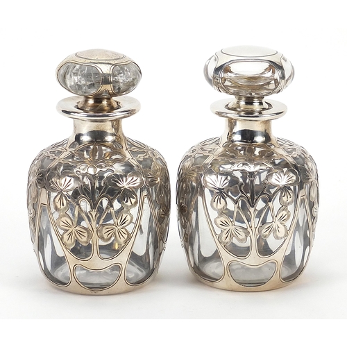 69 - Pair of unmarked silver overlaid glass scent bottles pierced with flowers, 11.5cm high