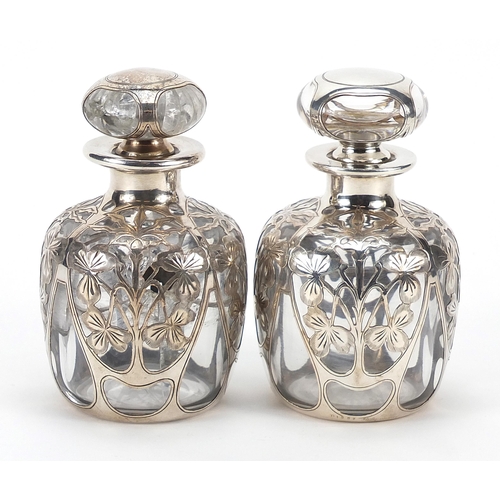 69 - Pair of unmarked silver overlaid glass scent bottles pierced with flowers, 11.5cm high