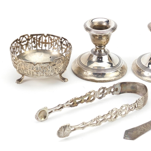 58 - Silver objects comprising pair of dwarf candlesticks, pair of open salts, sugar tongs and a spoon, v... 