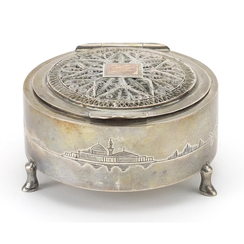 59 - Circular unmarked silver jewel box with hinged filigree lid and mirrored interior raised on three fe... 