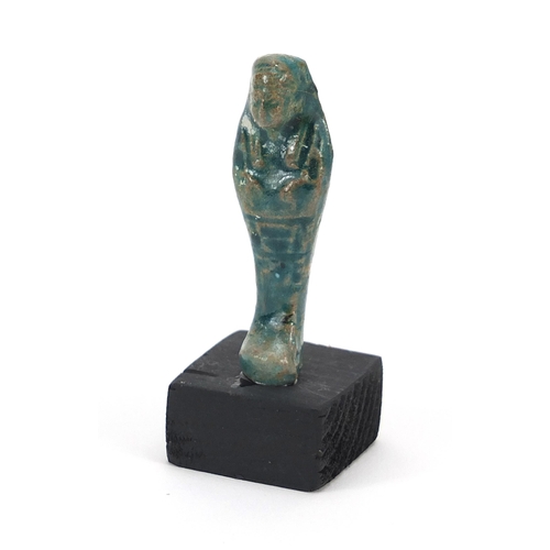 1525 - Egyptian style ushabti raised on a wooden base, overall 8cm high