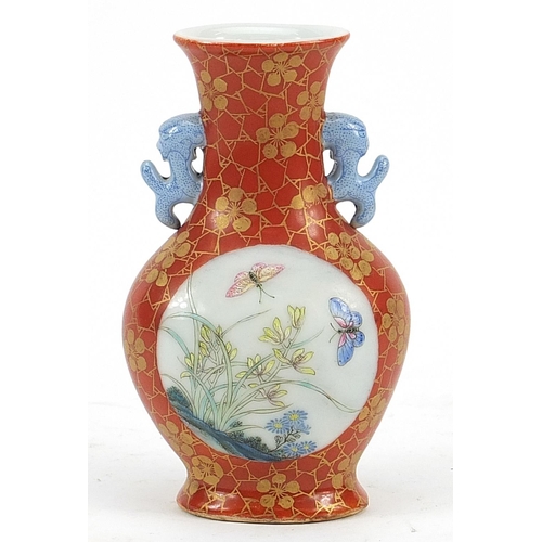 117 - Chinese iron red ground porcelain vase with twin handles hand painted in the famille rose palette wi... 