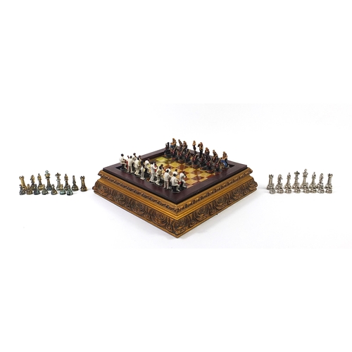 1744 - Ornate gilt framed chess board with metal pieces, the largest pieces each 7cm high