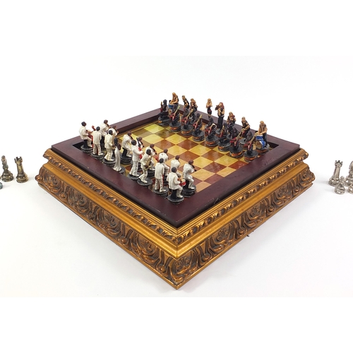 1744 - Ornate gilt framed chess board with metal pieces, the largest pieces each 7cm high