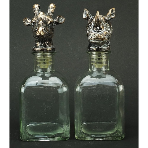 519 - Pair of glass decanters with bronzed rhinoceros and giraffe head stoppers, 24cm high