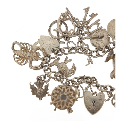 1036 - Silver charm bracelet with a selection of mostly silver charms, 49.0g