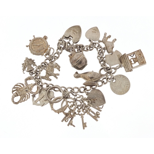 1036 - Silver charm bracelet with a selection of mostly silver charms, 49.0g