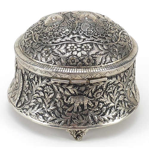 279 - Indian white metal box and cover decorated with figures amongst flowers, 17cm high x 21cm in diamete... 