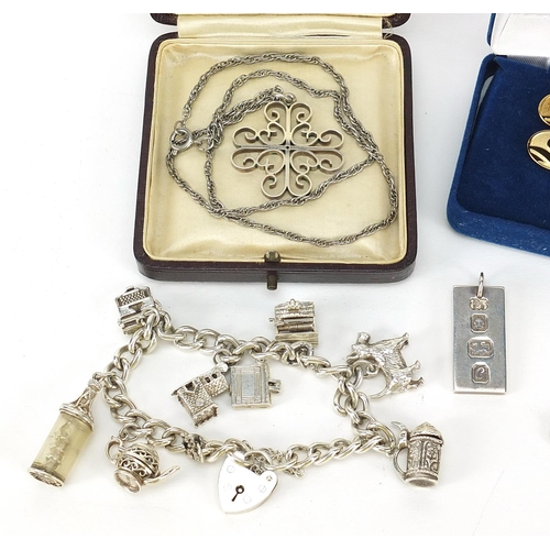 1141 - Silver jewellery including a charm bracelet, ingot on necklace, two silver gilt tie tacks and a thim... 