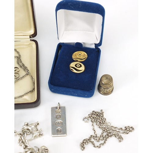 1141 - Silver jewellery including a charm bracelet, ingot on necklace, two silver gilt tie tacks and a thim... 