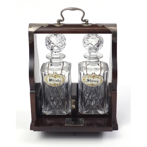 1519 - Two glass decanters housed in a mahogany tantalus with silver plated mounts, 29cm x 24.5cm W x 13cm ... 