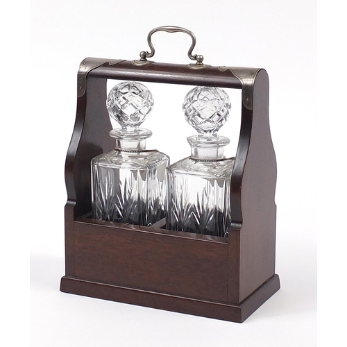 1519 - Two glass decanters housed in a mahogany tantalus with silver plated mounts, 29cm x 24.5cm W x 13cm ... 