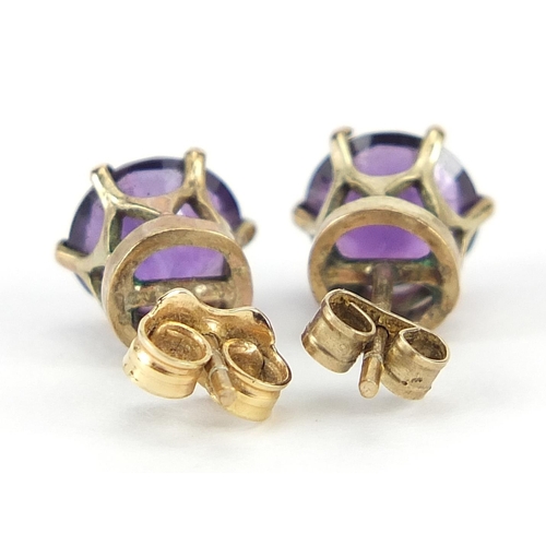 909 - Pair of 9ct gold amethyst solitaire stud earrings, 7mm in diameter, 1.6g