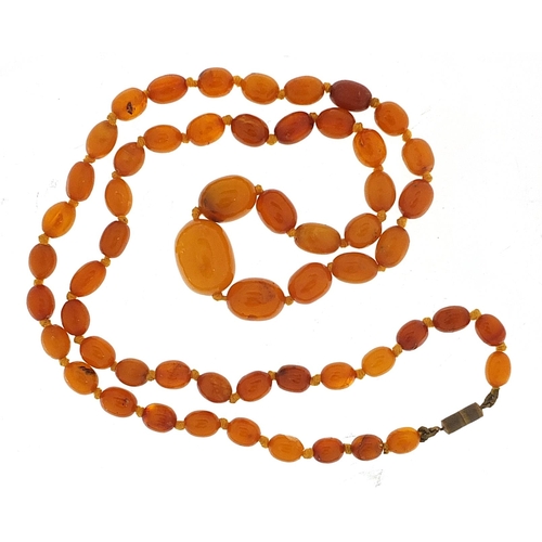 1042 - Butterscotch amber coloured graduated bead necklace, the largest bead 2.2cm in length, the necklace ... 