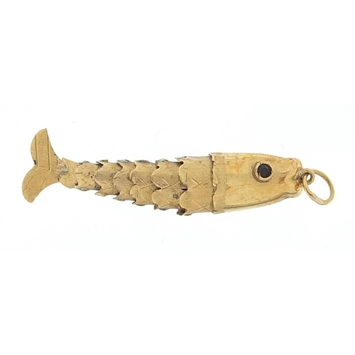 935 - 9ct gold articulated fish charm with garnet eyes, 3.5cm in length, 1.6g