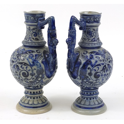 367 - Pair of German salt glazed jugs decorated with grotesque masks and foliage, 28cm high