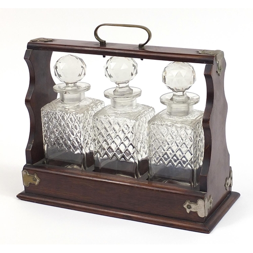 17 - Oak three bottle tantalus with three glass decanters, 35.5cm wide
