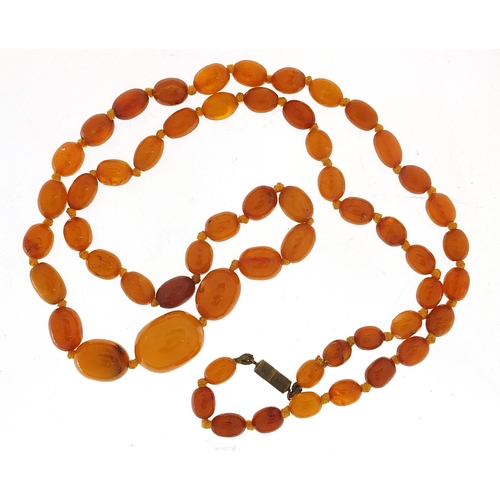 926 - Butterscotch amber coloured graduated bead necklace, the largest bead 2.2cm in length, the necklace ... 