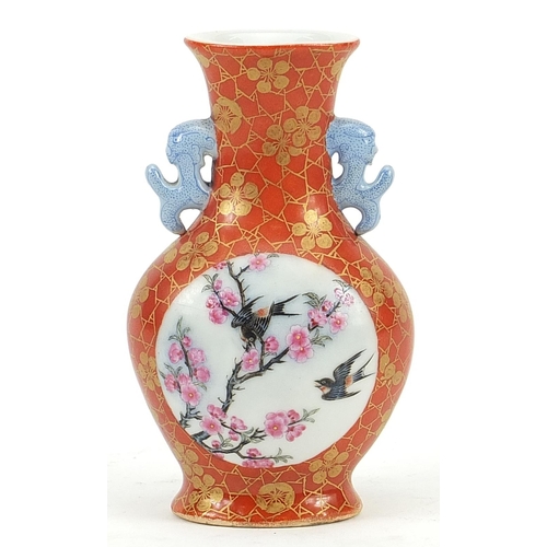 62 - Chinese iron red ground porcelain vase with twin handles hand painted in the famille rose palette wi... 