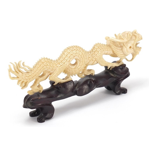 407 - Chinese ivory carving of a dragon raised on hardwood stand, 17.5cm in length