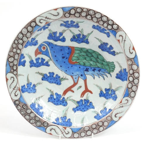 105 - Turkish Iznik pottery plate hand painted with a bird amongst flowers, 33cm in diameter