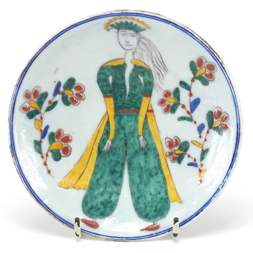 168 - Turkish pottery shallow dish hand painted with a figure and flowers, 14.5cm in diameter